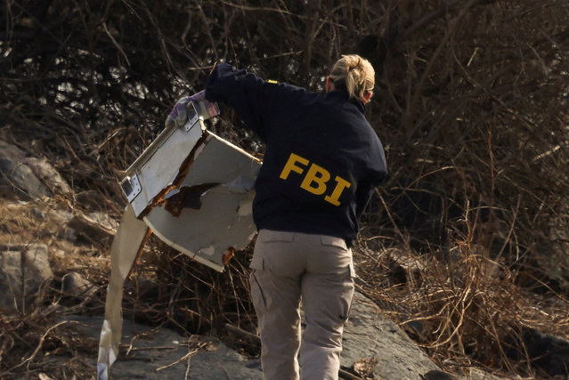 An FBI agent carries debris, after American Eagle flight 5342 collided with a Black Hawk helicopter while approaching Ronald Reagan Washington National Airport and crashed into Potomac River, in Arlington, Virginia on January 30, 2025. (Photo by Kevin Lamarque/Reuters)