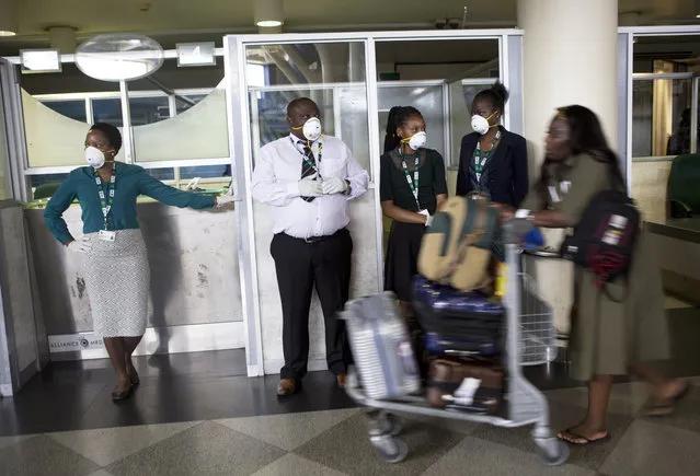 Travellers and airport staff, some wearing masks as a precaution against the coronavirus outbreak, walk through Robert Mugabe International airport in Harare, Wednesday, March, 11, 2020. For most people, the new coronavirus causes only mild or moderate symptoms, such as fever and cough. For some, especially older adults and people with existing health problems, it can cause more severe illness, including pneumonia. (Photo by Tsvangirayi Mukwazhi/AP Photo)