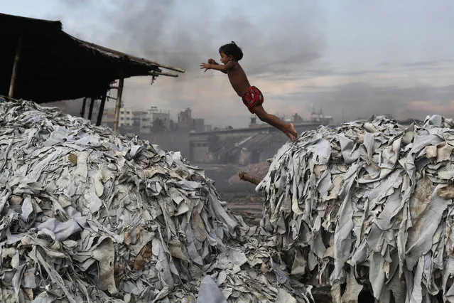 A child jumps on the waste products that are used to make poultry feed as she plays in a tannery at Hazaribagh in Dhaka October 9, 2012. Luxury leather goods sold across the world are produced in a slum area of Bangladesh's capital where workers, including children, are exposed to hazardous chemicals and often injured in horrific accidents, according to a study released on Tuesday. None of the tanneries packed cheek by jowl into Dhaka's Hazaribagh neighbourhood treat their waste water, which contains animal flesh, sulphuric acid, chromium and lead, leaving it to spew into open gutters and eventually the city's main river. (Photo by Andrew Biraj/Reuters)