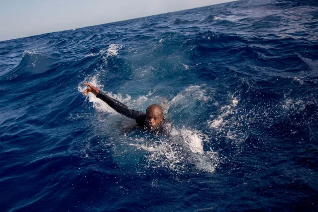 A migrant tries to board a boat of the German NGO Sea- Watch in the Mediterranean Sea on November 6, 2017. During a shipwreck, five people died, including a newborn child. According to the German NGO Sea- Watch, which has saved 58 migrants, the violent behavior of the Libyan coast guard caused the death of five persons. (Photo by Alessio Paduano/AFP Photo)