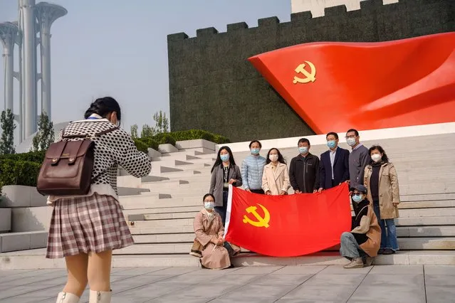 People wearing face masks pose for a photo holding the flag of the Communist Party of China the Museum of the Communist Party of China (CPC) in Beijing, China, 14 October 2022. The CPC museum is a site devoted to permanent and comprehensive exhibitions of the party's history. (Photo by Wu Hao/EPA/EFE)
