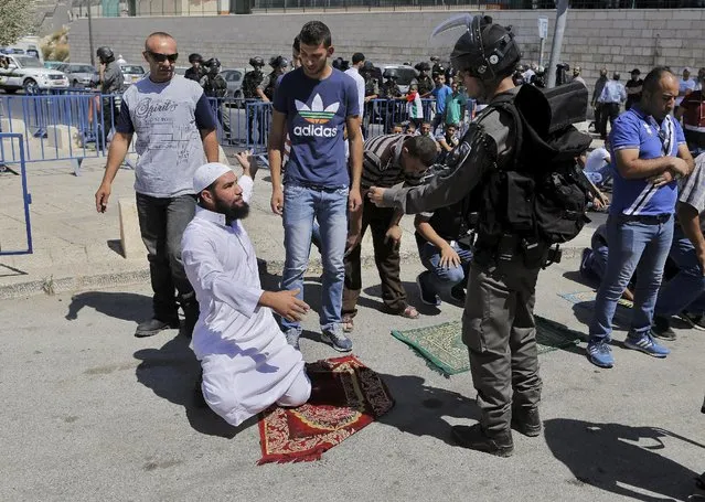 An Israeli border policeman speaks to a Palestinian man taking part in Friday prayers outside the Old City in Arab east Jerusalem neighbourhood of Ras al-Amud September 18, 2015. (Photo by Ammar Awad/Reuters)