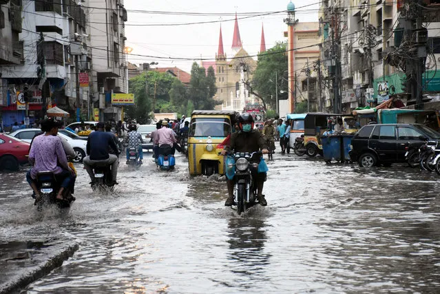 People ride motorcycles through a flooded road in southern Pakistani port city of Karachi, on July 6, 2020. (Photo by Xinhua/Stringer via Getty Images)
