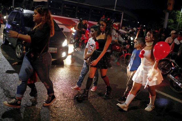 People walk near to a motorcycle ride called “Caravan of Terror”, in Caracas, Venezuela on October 29, 2022. (Photo by Leonardo Fernandez/Reuters)