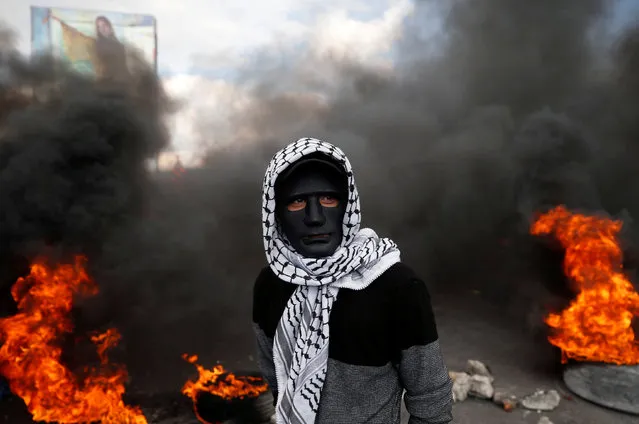 A Palestinian demonstrator stands near burning tires during clashes with Israeli troops at a protest against U.S. President Donald Trump's decision to recognise Jerusalem as the capital of Israel, near the West Bank city of Nablus December 15, 2017. (Photo by Mohamad Torokman/Reuters)