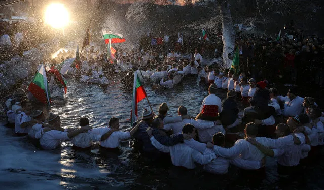 Bulgarian men dance in the waters of the Tundzha river during a celebration to commemorate Epiphany Day in the town of Kalofer, Bulgaria, January 6, 2018. (Photo by Stoyan Nenov/Reuters)