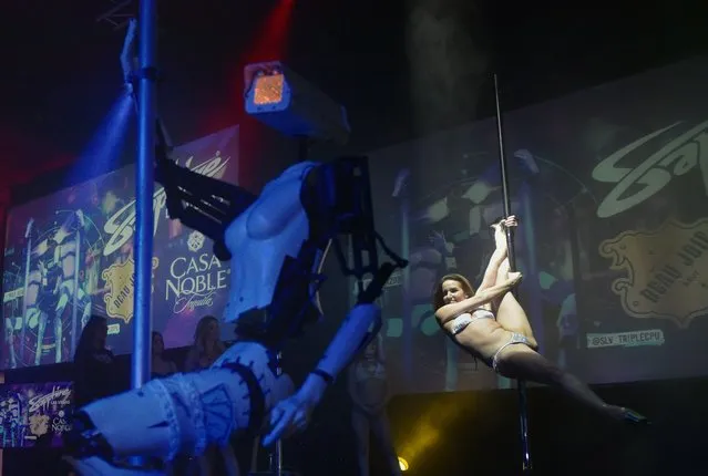 A human dancer performs next to a stripper robot at the Sapphire Gentlemen' s Club on the sidelines of CES 2018 in Las Vegas on January 8, 2018. (Photo by Mandel Ngan/AFP Photo)