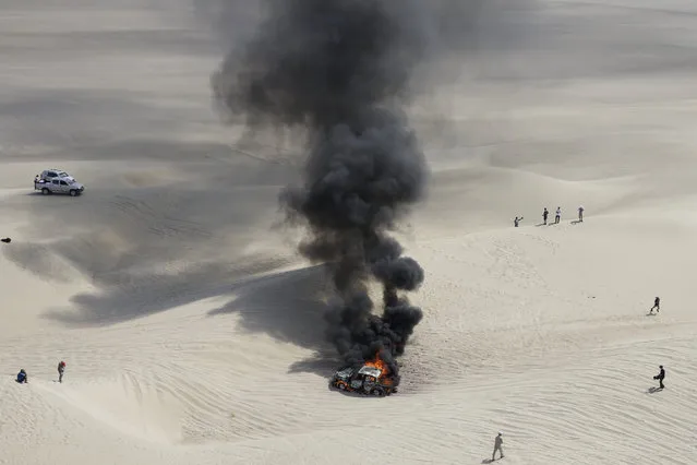 The Toyota of driver Alicia Reina and co-driver Carlos Dante Pelayo, both of Argentina, burns after catching fire during the third stage of the 2018 Dakar Rally in Pisco, Peru, Monday, January 8, 2018. (Photo by Ricardo Mazalan/AP Photo)