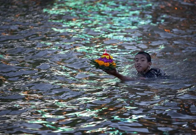 A Thai man with a krathong in the fast and full flowing Chao Phraya River on the Thai annual Loy Krathong festival, in Bangkok, Thailand, 06 November 2014. The Loy Krathong, festival of lights is held according to the Thai lunar calendar at full moon on the twelfth month across Thailand and dates back more than 700 years. (Photo by Narong Sangnak/EPA)