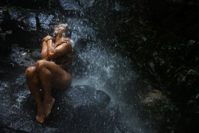 Anda Oliveira, 34, enjoys a waterfall in the Tijuca National Park, one of the world's biggest urban forests, marking the World Water Day in Rio de Janeiro, Brazil on March 15, 2024. (Photo by Pilar Olivares/Reuters)