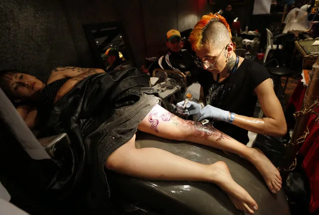 A woman has her leg tattooed during the VIII International Convention of Tattoo artists in Bogota, Colombia, Saturday, November 15, 2014. (Photo by Fernando Vergara/AP Photo)