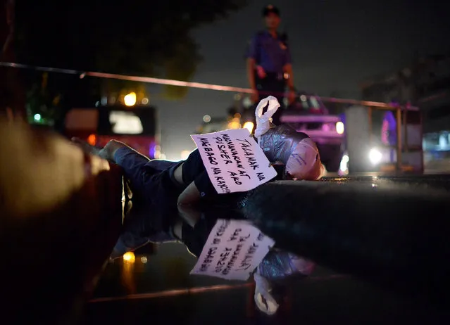 The body of a man, with his head wrapped in a masking tape is pictured on a street, who police said is a victim of drug related vigilante execution in Manila, Philippines September 20, 2016. A sign on a piece of paper also found tied on the victim's head, “Talamak na Magnanakaw at Pusher Ako Magbago na Kayo” reads: “I am a persistent thief and drug pusher, Better Change”. (Photo by Ezra Acayan/Reuters)