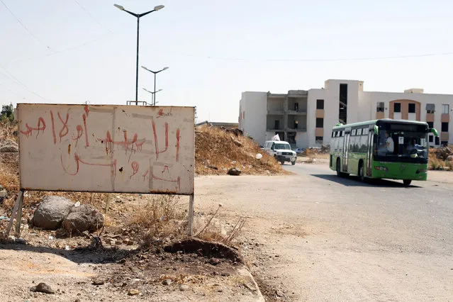 A bus with Syrian rebels and their families evacuating the besieged Waer district in the central Syrian city of Homs is pictured after a local agreement reached between rebels and Syria's army, Syria, September 22, 2016. The graffiti on the sign reads in Arabic: “Assad or nobody, only Bashar”. (Photo by Omar Sanadiki/Reuters)