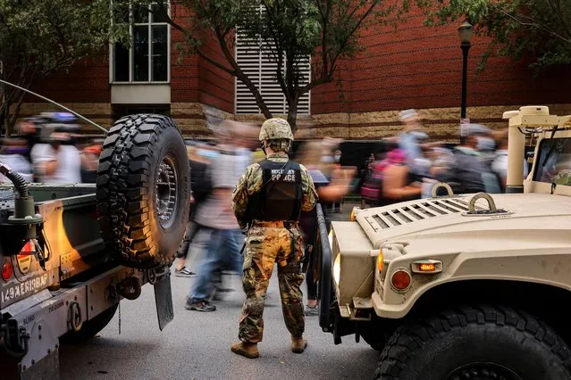 Protesters march past a military police officer guarding an area a day after a grand jury considering the March killing of Breonna Taylor, a Black medical worker, in her home in Louisville, Kentucky, voted to indict one of three white police officers for wanton endangerment, in Louisville, Kentucky, U.S. on September 24, 2020. (Photo by Carlos Barria/Reuters)