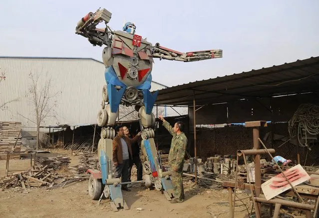 Yao Fuxing points to his replica of transformer Optimus Prime, at a yard in Hejian Hebei province, November 24, 2014. Yao made the replica out of parts from scrapped cars, motorbikes and farm vehicles, as a gift for his son's 18th birthday, according to local media. (Photo by Reuters/China Daily)