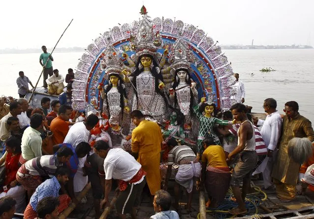 Devotees load an idol of Hindu goddess Durga onto a boat as it is being transported for immersion in the waters of the river Ganges on the last day of the Durga Puja festival in Kolkata, India, October 22, 2015. (Photo by Rupak De Chowdhuri/Reuters)
