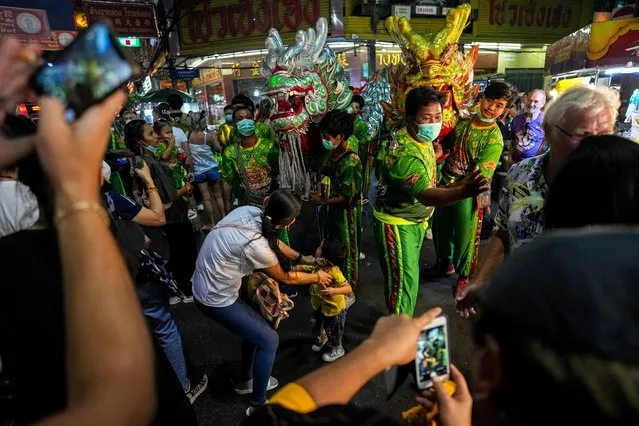 Tourists take pictures as dancers perform with dragons ahead of Lunar New Year in Bangkok's Chinatown, Thailand on January 19, 2023. (Photo by Athit Perawongmetha/Reuters)