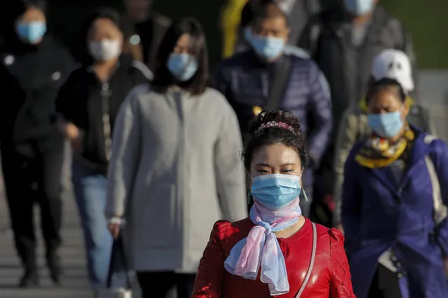 People wearing face masks to help curb the spread of the coronavirus walk across a street during the morning rush hour in Beijing, Tuesday, October 13, 2020. (Photo by Andy Wong/AP Photo)