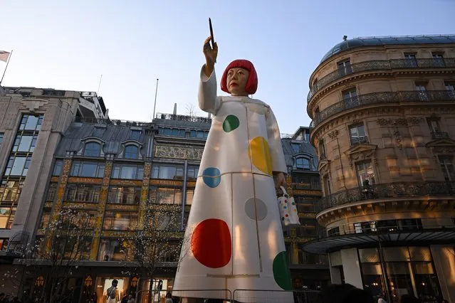This photograph taken on March 2, 2023, shows a large statue depicting Japanese contemporary artist Yayoi Kusama pointing a paintbrush towards the French luxury brand Louis Vuitton headquarters in Paris. (Photo by Stefano Rellandini/AFP Photo)