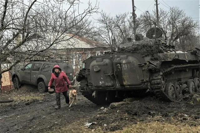 A woman walks past a destroyed BMP-2 tank after a shelling in the village of Chasiv Yar on March 11, 2023 amid the Russian invasion of Ukraine. (Photo by Aris Messinis/AFP Photo)