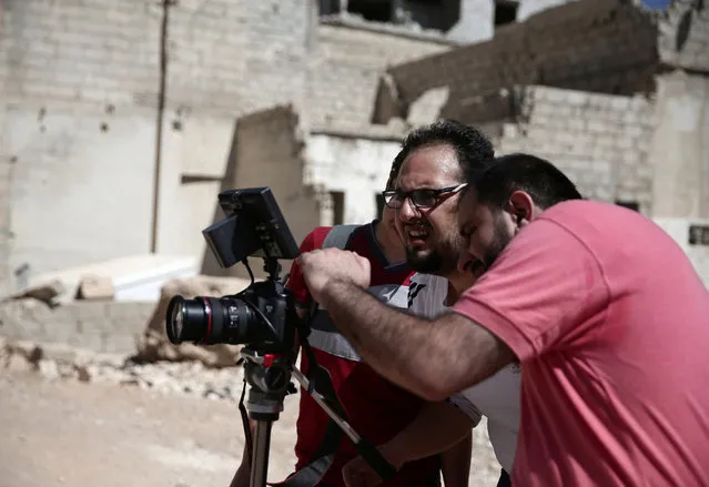 Syrian director Humam Husari (R) and cameraman Sami al-Shami (C) operate a camera as they film a scene  in the rebel-held besieged town of Zamalka, in the Damascus suburbs, Syria September 19, 2016. (Photo by Bassam Khabieh/Reuters)