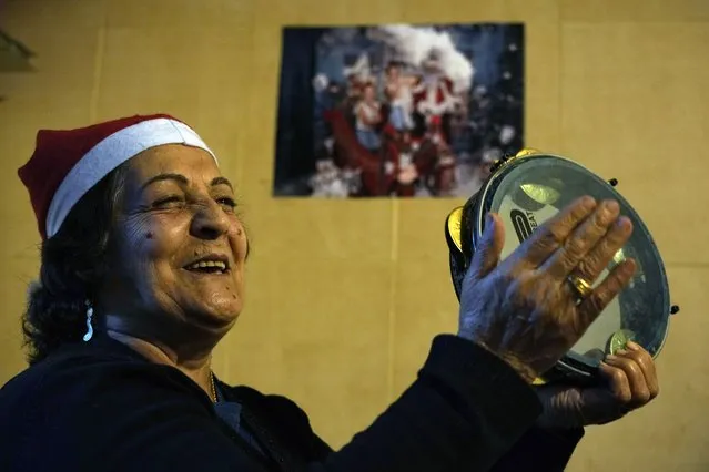 Palestinian Afife Atieh plays the tambourine during community Christmas dinner for elderly residents at the only majority-Christian Palestinian refugee camp, in Dbayeh, north of Beirut, Lebanon, Wednesday, December 21, 2022. Hundreds of thousands of Palestinians fled or were forced from their homes during the 1948 Mideast war over Israel's creation. Today, several million Palestinian refugees and their descendants are scattered across Jordan, Syria and Lebanon, as well as the West Bank and Gaza, lands Israel captured in 1967. (Photo by Bilal Hussein/AP Photo)