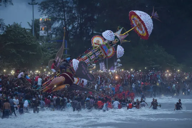 Indonesian Muslims cast a hoyak tabuik, a model of a mythical Islamic steed, into the sea during the Hoyak Tabuik festival in Pariaman on West Sumatra on October 16, 2016. Huge models of mythical Islamic steeds were carried aloft amid crowds before being hurled into the sea October 16, at the peak of a colourful festival in Indonesia. Thousands of people flocked to a picturesque stretch of coastline on western Sumatra island for Tabuik, an annual event that attracts hordes of foreign and local tourists. (Photo by Adek Berry/AFP Photo)
