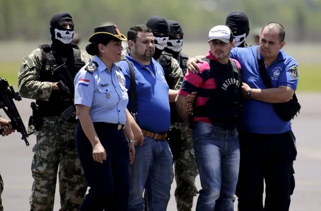 Former Paraguayan Mayor Vilmar Acosta (2nd R) is being escorted by soldiers and members of an anti-kidnapping unit after his arrival at a military base in Luque, Paraguay, November 17, 2015. Acosta was extradited from Brazil to face questioning in the case of the murder of prominent ABC journalist Pablo Medina. (Photo by Jorge Adorno/Reuters)