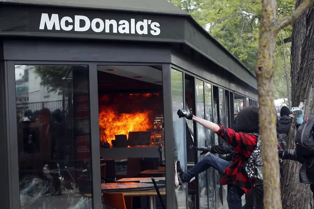 A McDonald's restaurant is hit with petrol bombs thrown by activists during the traditional May Day rally in the center of Paris, France, May 1, 2018. Each year, people around the world take to the streets to mark International Workers' Day, or May Day. (Photo by Francois Mori/AP Photo)