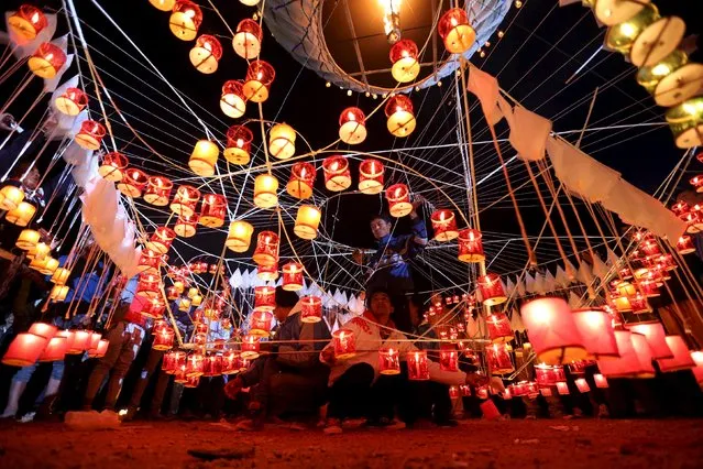 People light candles before releasing a traditional home-made paper balloon into the sky during the annual Tazaungdaing festival in Taunggyi, Myanmar November 19, 2015. (Photo by Soe Zeya Tun/Reuters)