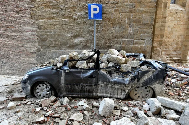 A photo taken on October 28, 2016 shows a damaged car in the “red zone”, an area cordoned off for safety reasons, in Camerino, where 80 per cent of the houses have been left uninhabitable after two earthquakes hit the region. Italy on October 28 vowed to rebuild every home destroyed after two powerful earthquakes that forced thousands to flee in terror but "miraculously" did not cause any fatalities. Following two powerful 6.1 and 5.5 magnitude quakes on October 26 which left almost 5,000 people homeless, Italy's national geophysics institute (INGV) has recorded almost 700 tremors, with experts saying they could go on for weeks or months. (Photo by Alberto Pizzoli/AFP Photo)