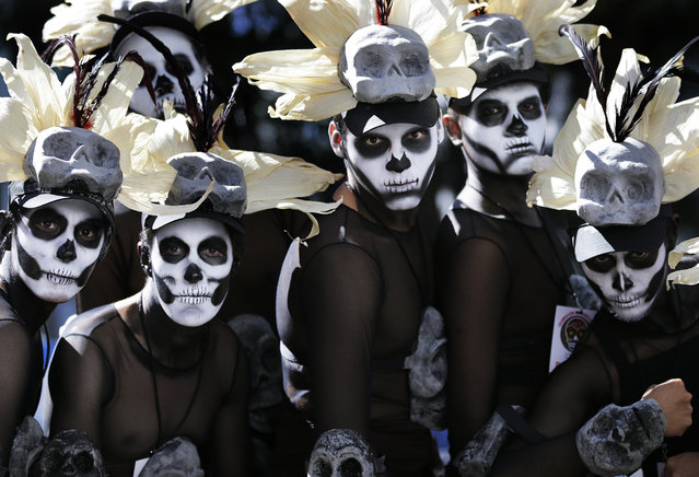 Men dressed in costumes wait for a Day of the Dead parade to begin along Mexico City's main Reforma Avenue, Saturday, October 29, 2016. Mexico's Day of the Dead celebrations, which traditionally consisted of quiet family gatherings at the graves of their departed loved ones are fast changing under the influence of Hollywood movies, zombie shows, Halloween and even politics. Mexico's capital was holding its first Day of the Dead parade an idea actually born out of the imagination of a scriptwriter for last year's James Bond movie “Spectre”. In the film, whose opening scenes were shot in Mexico City, Bond chases a villain through crowds of revelers in what resembled a parade of people in skeleton outfits and floats. (Photo by Marco Ugarte/AP Photo)