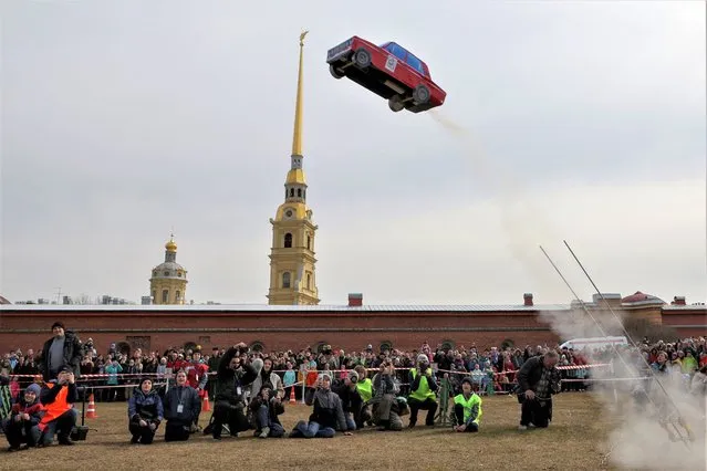 Spectators watch the launch of a model rocket depicting a Soviet-made retro VAZ car during a show dedicated to Cosmonautics Day near the Peter and Paul Fortress in Saint Petersburg, Russia on April 16, 2023. (Photo by Anton Vaganov/Reuters)