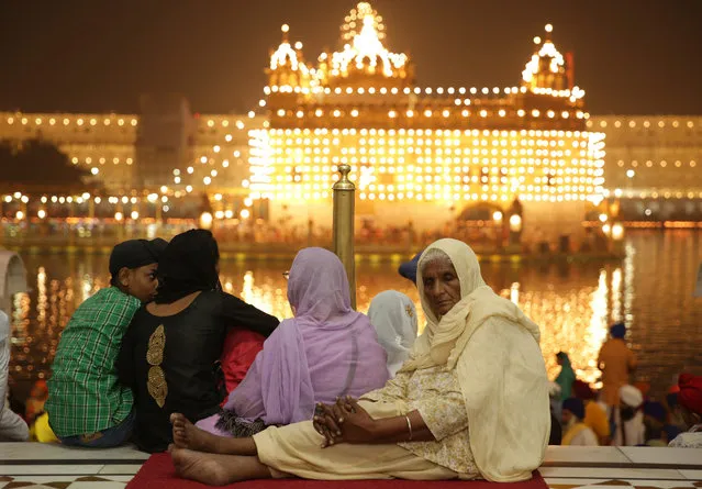 An elderly woman listens to religious hymns while visiting the Golden Temple, the holiest of Sikh shrines, seen in the background, on the occasion of Diwali festival and Bandi Chorh Diwas in Amritsar, India, 30 October 2016. Devotees started to arrive at the Golden Temple in the pre-dawn hours to seek blessings on Diwali festival. The festival coincides with the Bandi Chorh Diwas which is also celebrated at the Golden Temple to mark the return of Guru Hargobind, the sixth Guru or the Master of the Sikhs, to Amritsar after his release from Gwalior fort during the reign of Mughal emperor Jahangir. (Photo by Raminder Pal Singh/EPA)