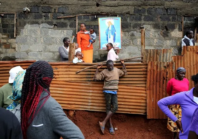 Faithful stand as Pope Francis arrives at the Kangemi slum on the outskirts of Kenya's capital Nairobi, November 27, 2015. (Photo by Goran Tomasevic/Reuters)