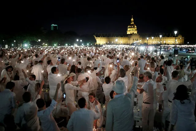 People react at their tables near Les Invalides during the Diner en Blanc (Dinner in White) in Paris, France, June 3, 2018. Diners dressed head to toe in white and bringing with them white tablecloths, glassware and other finery, gather for an impromptu open-air dinner, which takes place at a different place in Paris every year. (Photo by Benoit Tessier/Reuters)