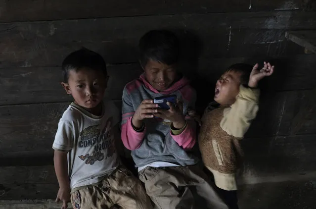 Tangkhul Naga children watch a video on a mobile phone inside their kitchen in Shangshak village, in the northeastern Indian state of Manipur, Tuesday, Jan. 19, 2021. Nagas are in indigenous people inhabiting several northeastern Indian states and across the border in Myanmar. (Photo by Yirmiyan Arthur/AP Photo)