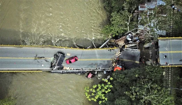 Cars sit on and under the El Alambrado bridge after it collapsed the previous day in Caicedonia, Colombia, Thursday, April 13, 2023. Two people died and over a dozen were injured, according to authorities. (Photo by Andres Quintero/AP Photo)