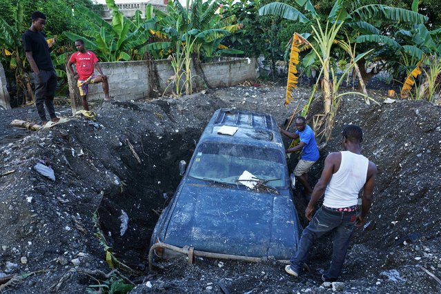 Residents work to remove a partially buried vehicle in the aftermath of Hurricane Melissa in Petit-Goave, Haiti, Thursday, November 6, 2025. (Photo by Odelyn Joseph/AP Photo)