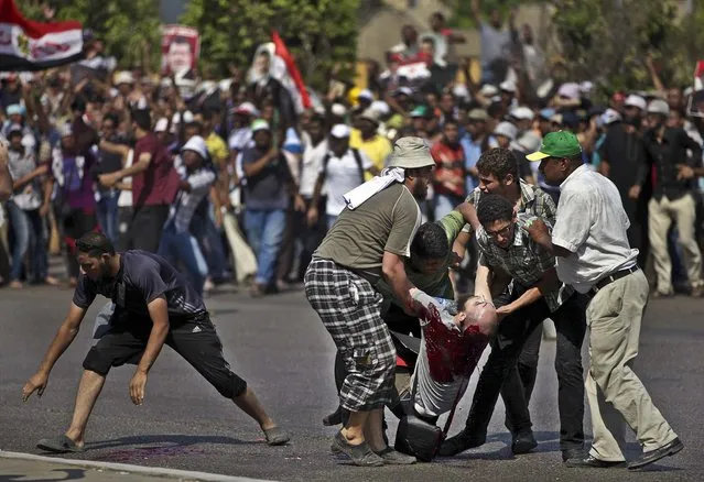 Supporters of ousted Egypt's President Mohammed Morsi pick up the body of a man shot near the Republican Guard building in Cairo, on July 5, 2013. Egyptian troops opened fire on mostly Islamist protesters. (Photo by Khalil Hamra/Associated Press)