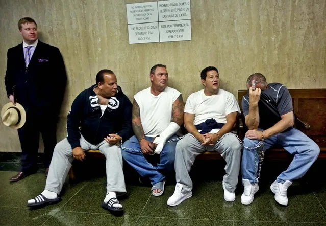 Defendants Anthony Santoro, Anthony Urban, Vito Badano, and Nicholas Bernhard, seated left to right, wait in handcuffs in a courtroom hallway with attorney Timothy Parlatore, for arraignment, in New York, on July 9, 2013. Nine people, members of the infamous Bonanno crime family, have been indicted on enterprise corruption charges. (Photo by Richard Drew/Associated Press)