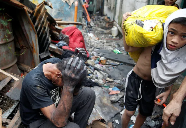 A resident carries a plastic bag containing belongings past a fellow victim, after a fire in the residential district of Addition Hills in Mandaluyong, Metro Manila, Philippines, November 14, 2016. A fire that raged for seven hours through a crowded Manila slum community killed two people and left close to 1,500 families homeless, fire authorities said on Monday. More than 5,000 people were temporary housed in four public schools in Mandaluyong City, to the east of downtown Manila, as fire protection officials investigated the cause of the fire, which destroyed more than 500 houses on Sunday. Damage was estimated at $203,800. A blaze destroyed 800 houses in the same community last year. “The fire spread rapidly because the houses were made of light materials and the roads were so narrow”, a fire official said, adding the two casualties had been trapped in their homes. (Photo by Erik De Castro/Reuters)