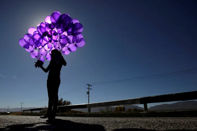 An activist holds purple balloons at El Navajo creek, where the bodies of several women were found, during a ceremony to mark the International Day for the Elimination of Violence Against Women in Praxedis G. Guerrero, on the outskirts of Ciudad Juarez, Mexico, November 24, 2017. (Photo by Jose Luis Gonzalez/Reuters)