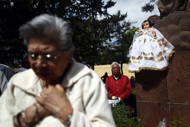 A dressed-up doll representing baby Jesus is seen perched on a wall as people pray nearby during a celebration 40 days after the birth of Jesus in Xochimilco, on the outskirts of Mexico City, February 2, 2015. (Photo by Edgard Garrido/Reuters)