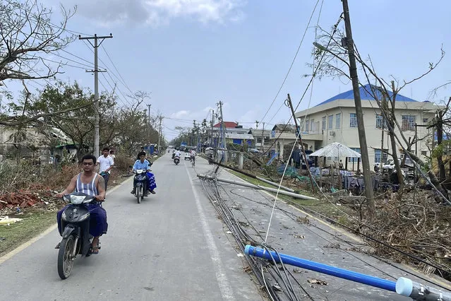 Local people ride motorbike with lamp-posts fallen on a roadside after Cyclone Mocha in Sittwe township, Rakhine State, Myanmar, Friday, May 19, 2023. Cyclone Mocha roared in from the Bay of Bengal on Sunday with high winds and rain slamming a corner of neighboring Bangladesh and a wider swath of western Myanmar's Rakhine state. (Photo by AP Photo/Stringer)
