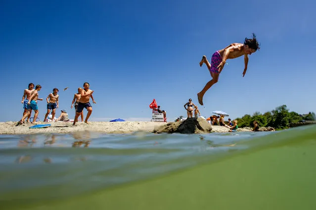Teenagers jump into the creek at Good Harbor Beach in Gloucester, Massachusetts on July 7, 2023. (Photo by Joseph Prezioso/AFP Photo)