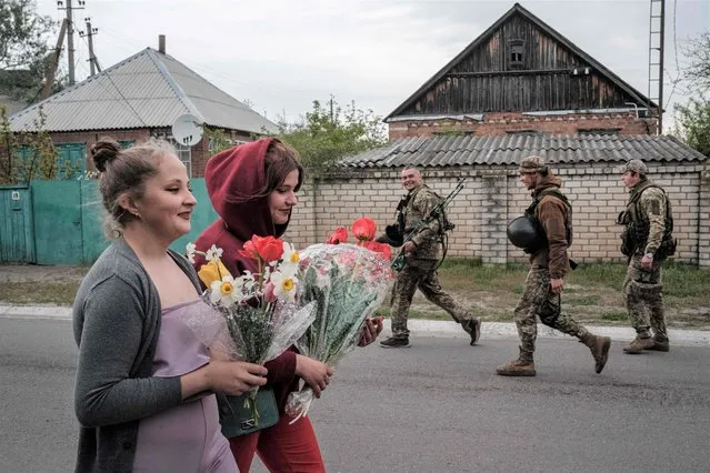 Ukrainian cousins Nastya (L), 16, and Polina, 15, bring flowers to their mothers for a birthday at their home as heavy shelling can be heard in the distance in Raihorodok, eastern Ukraine, on May 2, 2022, amid the Russian invasion of the country. (Photo by Yasuyoshi Chiba/AFP Photo)