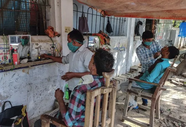 Wayside barbers wearing masks as a precaution against the coronavirus attend to their customers in Prayagraj, India,  Monday, April 19, 2021. (Photo by Rajesh Kumar Singh/AP Photo)
