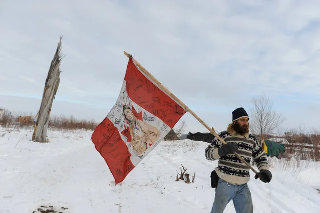 A man walks with the flag of an Indian nation in Oceti Sakowin camp during a protest against plans to pass the Dakota Access pipeline near the Standing Rock Indian Reservation, near Cannon Ball, North Dakota, U.S. December 2, 2016. (Photo by Stephanie Keith/Reuters)