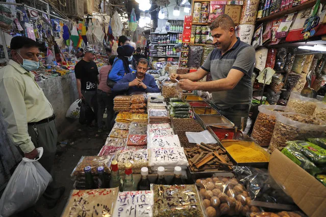 An Iraqi man sells food at the Shorja market in central Baghdad on April 12, 2021 ahead of the Muslim holy month of Ramadan after the easing of the curfew imposed by authorities amid the coronavirus COVID-19 pandemic. (Photo by Ahmad Al-Rubaye/AFP Photo)